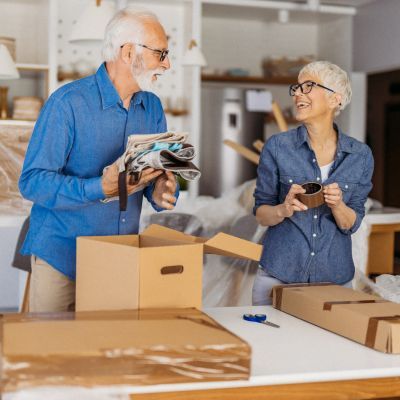 image shows an older couple packing their belongings into boxes