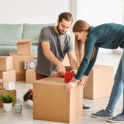 image shows a younger couple taping moving boxes